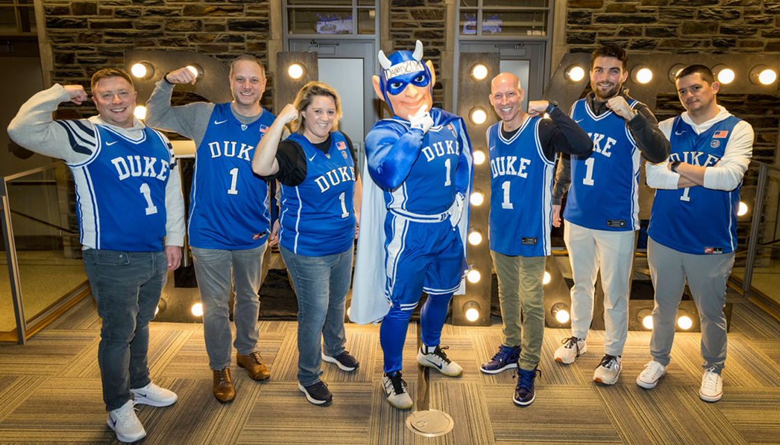 TRM Labs team members posing with the Duke Blue Devil mascot in Duke basketball jerseys
